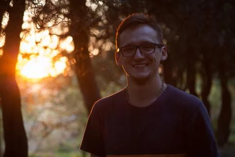 Young smiling man looking at camera at sunset in the green park 1 Stock-Fotos