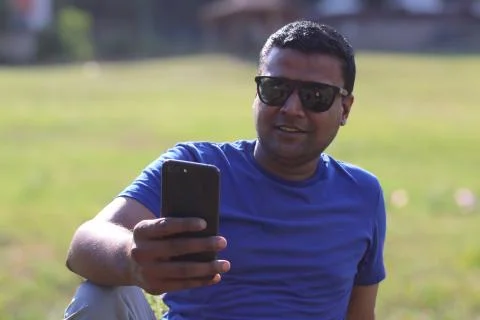 Young smiling man looking at his mobile in happy mood Stock Photos