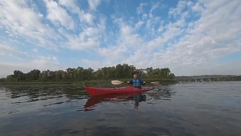 Young smiling man paddle boarding in cloudy day on sunrise. Slow motion shot Stock Footage 117113708