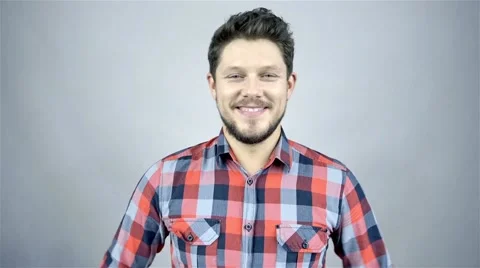 Young smiling man in a red checkered shirt on grey background Stock Footage 41795390