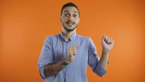 Young smiling man in shirt doing winner happy dance, presenting to side with Stock Footage 138504963