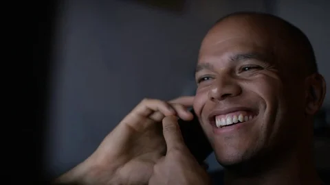 Young smiling man talking on his phone as he uses his computer at the same time Video stock 79193755