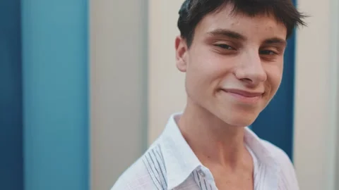 Young smiling man turns his head and smiles while looking at the camera on 스톡 동영상 254915144