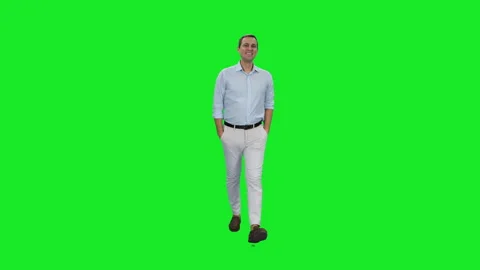 Young smiling man walking in light-colored shirt and pants on green background Stock Footage 269003728