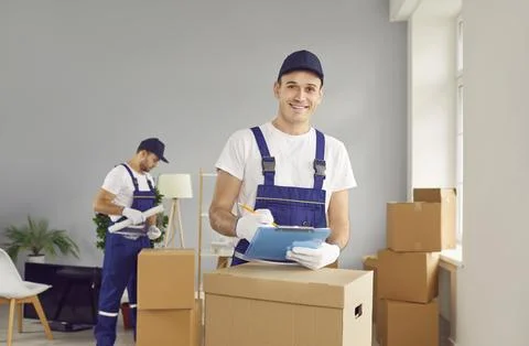 Young smiling mover man checking items list for moving, individual or company Stock Photos