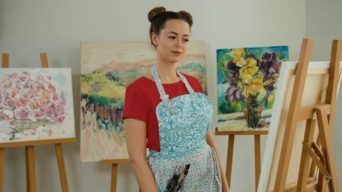 Young smiling painter posing on camera in her art studio full of masterpieces Stock Footage 74196313
