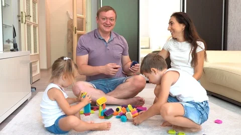 Young smiling parents and two little children playing board game at home Stock Footage 124632027
