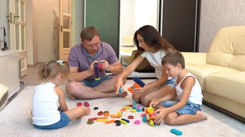 Young smiling parents and two little children playing board game at home Stock Footage 124632029