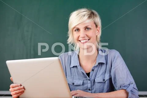 Young smiling teacher with laptop at school Stock Photos