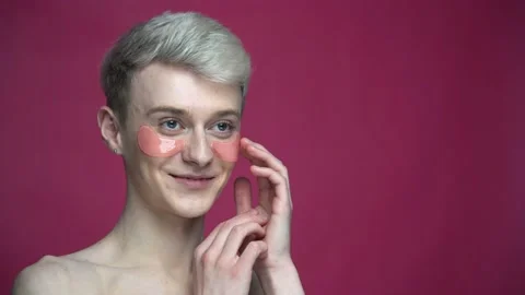 Young smiling transgender using eye patches looking at mirror at home Stock-Footage 153630939