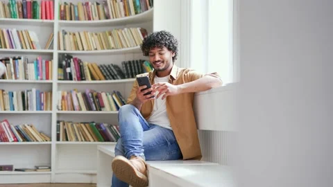 Young smiling university student using smartphone while sitting on bench  Stock Footage 239734064
