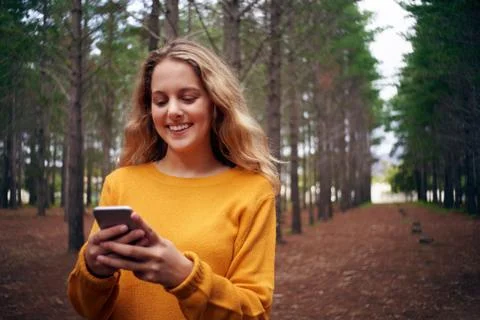 Young smiling woman in the forest using mobile phone Stock Photos