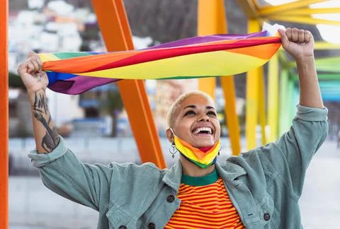 Young smiling woman holding rainbow flag symbol of Lgbtq social movement Stock Photos