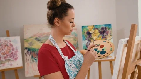 Young smiling woman posing on camera and painting her new masterpiece Stock Footage 74199032