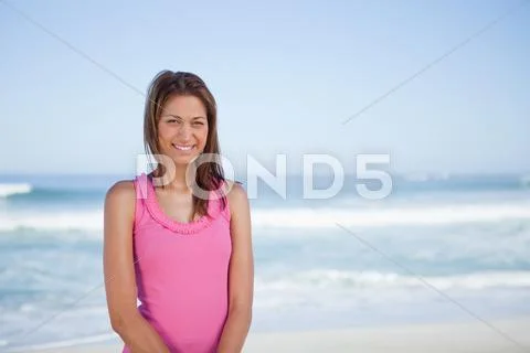 Young smiling woman standing upright in front of the sea Stock Photos
