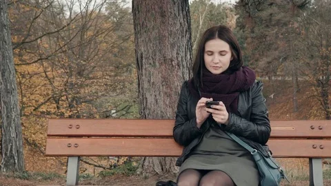 Young Smiling Woman Using Smartphone Sitting On Bench In Park. Beautiful Stock Footage 82932289