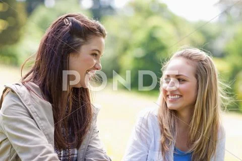 Young smiling women looking at each other in a parkland Stock Photos