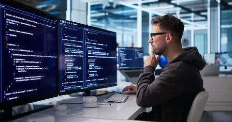 Young Software Engineer Coding Secure Platform At Desktop In Office Workspace Stockfoto's