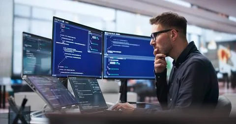 Young Software Engineer Uses Laptop And Touchscreen To Develop Secure Algorit Stock Photos