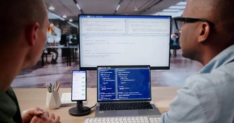 Young Software Engineer Working On Mobile App Code Across Laptop And Desktop. Foto stock