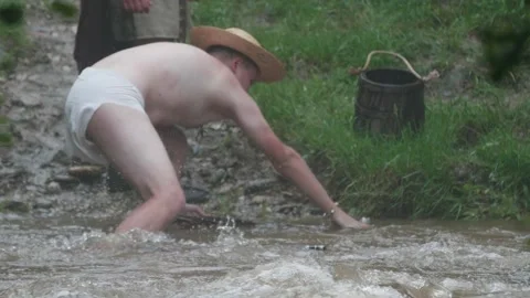 Young soldier dressed only in subligaculum, fishes in a fast mountain river Stock Footage 146310639
