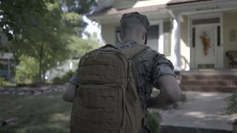 Young soldier walks up to house Stock Footage