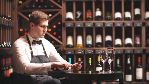 Young sommelier takes notes on his smartphone to work in a wine boutique Stock Photos
