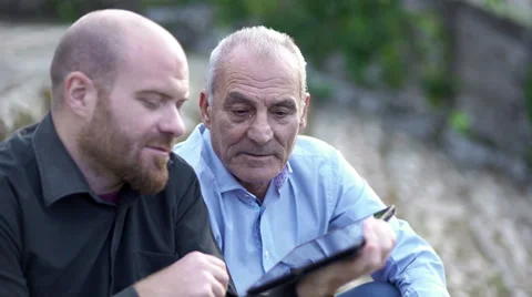 Young son explain to the old father how to use your tablet Stock Footage 68572407