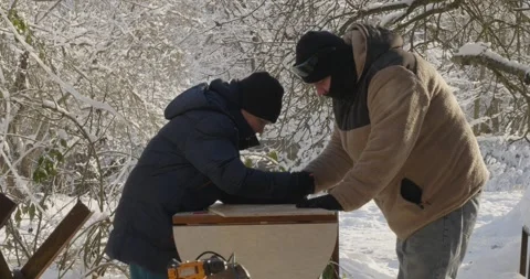 Young son learning from his father how to build a wooden bird feeder in a snowy Video stock 329279939