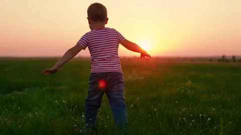 Young son plays on lawn, kid fly dream. Slow motion. Happy little boy plays Stock Footage 330069073