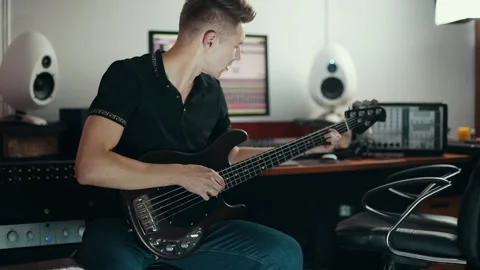 Young sound engineer trying to play on bass guitar in the studio 動画素材 305451739