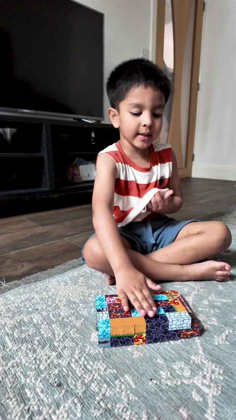 Young South Asian Boy Solving Colorful Magnetic Block Puzzle on Rug. vertical Stock Footage 338026720