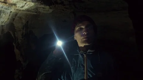 Young Speleologist standing in narrow cave with flashlight in his hand Stock Footage 80053683