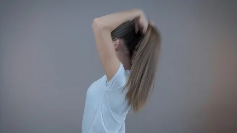 A young sports model demonstrates her long hair, I'm in the studio on a gray Stock Footage 95087053