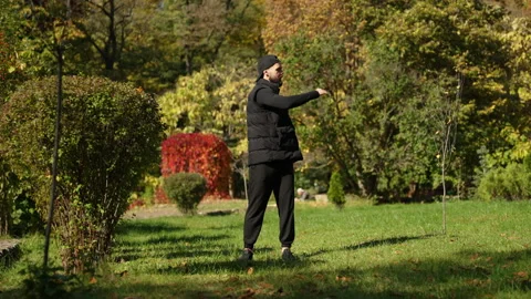 A young sportsman is doing warm-up in the autumn park Stock Footage 229872853