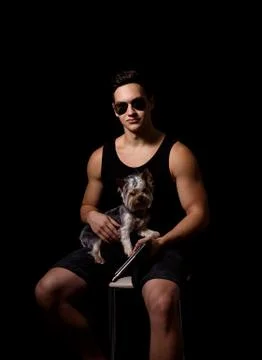 Young sporty guy with a dog on a black background. studio photo Photos