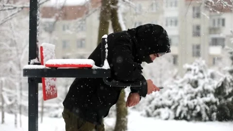 Young sporty man using smart phone in winter snowfall on sport area outside Video stock 167283320