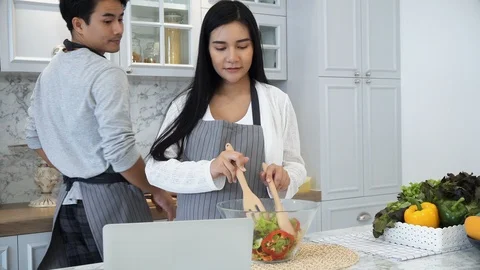 The young spouses use laptop computer while cooking in kitchen Stock Footage 87490591