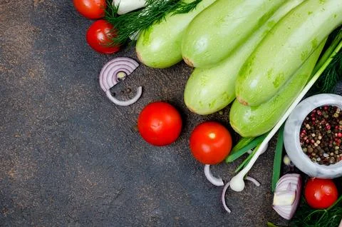 Young spring zucchini, tomatoes, herb and spices on black background Stockfoto's