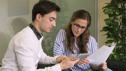Young staff discuss working issues using tablet while sitting in modern office. Stock Footage 82235970