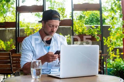 Young start up. Man use smartphone while working at laptop computer, Stock Photos