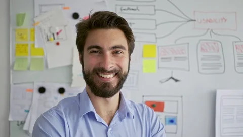 Young startup entrepreneur smiling at camera in front of office whiteboard Stock Footage 109351053