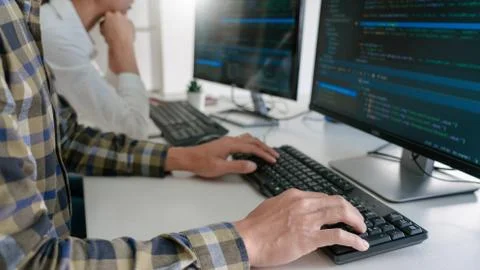 Young startup Programmers Sitting At Desks Working On Computers screen for De Stock-Fotos