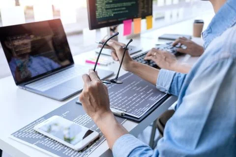 Young startup Programmers Sitting At Desks Working On Computers screen for De Stockfoto's