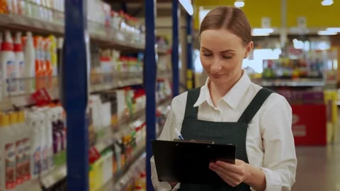 Young store manager writes products list in department Stock Footage 202307359