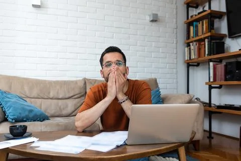 Young stressed man having issue with utility bills expense, sitting at home.. Stock Photos