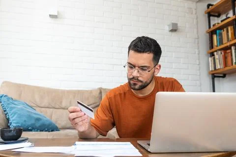 Young stressed man having issue with utility bills expense, sitting at home.. Stock Photos