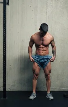 Young strong man posing and flexing his quadriceps legs muscles Фото