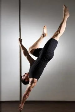 Young strong pole dancer smiling man in black clothes on pylon. White backgro Stock Photos