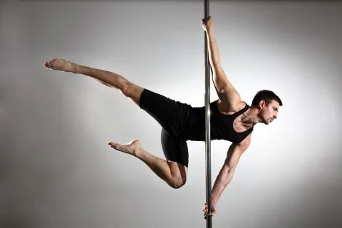 Young strong pole dancer smiling man in black clothes on pylon. White backgro Stock Photos